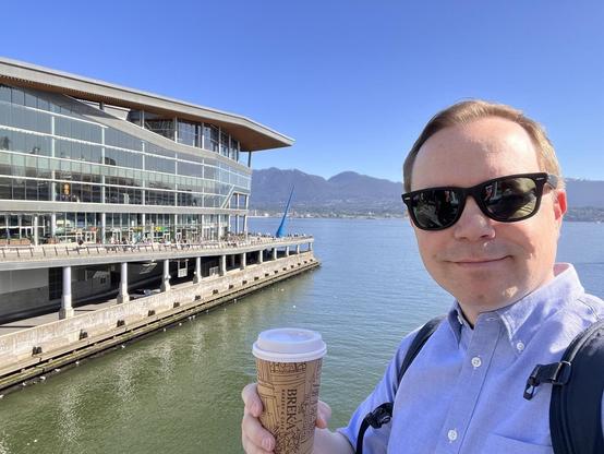 Chad selfie in front of the Vancouver Convention Center holding a coffee on a gorgeous clear day