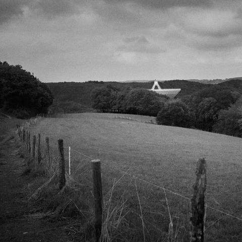 The picture shows a hilly, wooded landscape with a parabolic antenna pointing vertically upwards.