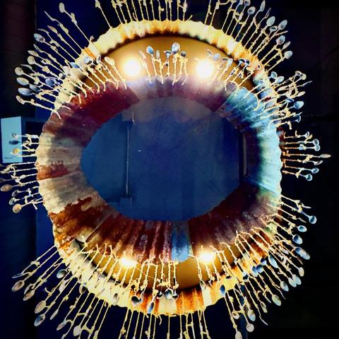 A large, elliptical chandelier comprised of hanging spoons vaguely resembles a kind of predatory fish when viewed from directly below.