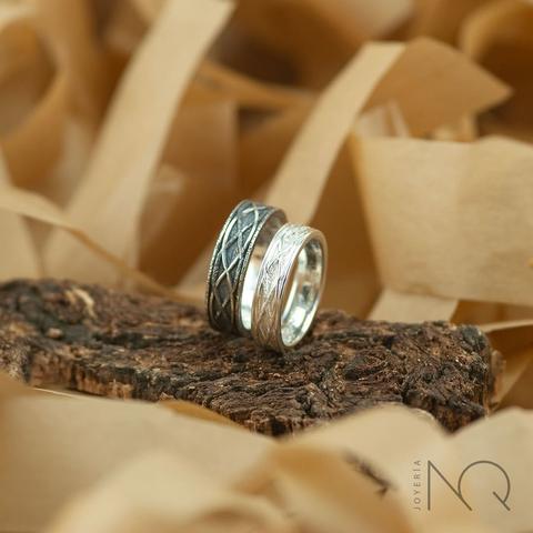 foto mas a detalle de las alianzas anteriores, la grande es mas oscura con solo un par de líneas blancas y parece mellada y en bruto, la pequeña es de plata blanca y bien pulida pero con 2 líneas mas oscuras al estiro de su compañera.