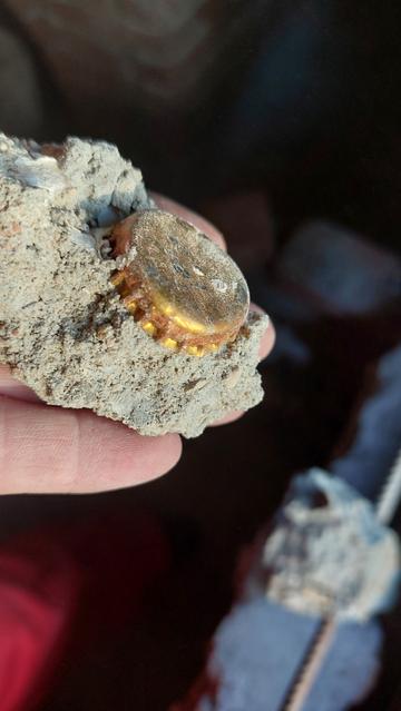 Ein Bruchstück alter Beton mit einem Kronkorken drin