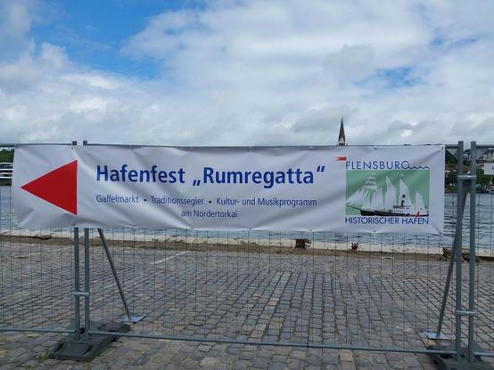 Banner mit Aufschrift "Hafenfest Rumregatta" am Zaun des Flensburger Museumshafens