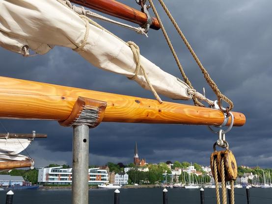 Besanbaum der Windsbraut mit angeschlagenem Segel. Der Himmel ist dramatisch dunkel mit Gewitterwolken