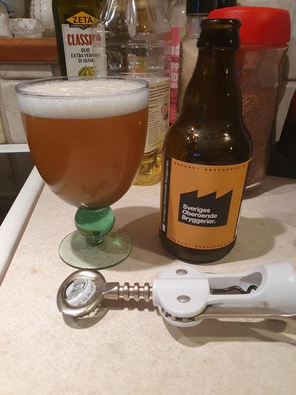 En kupa gult öl med ljus skumkrona. Flaskan har etiketten "Sveriges Oberoende Bryggerier."