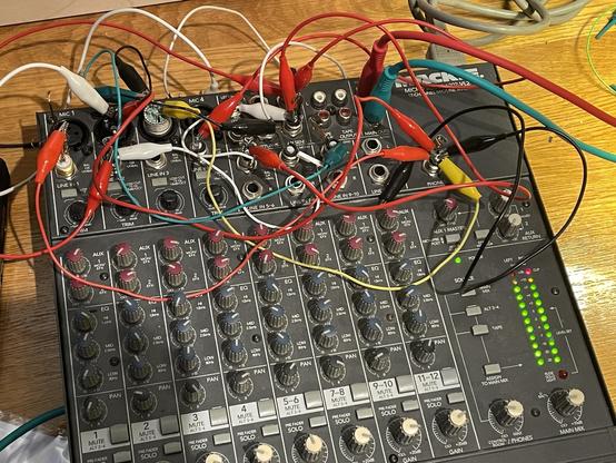 A Mackie 1202 mixer with crocodile cables connecting the inputs and outputs
