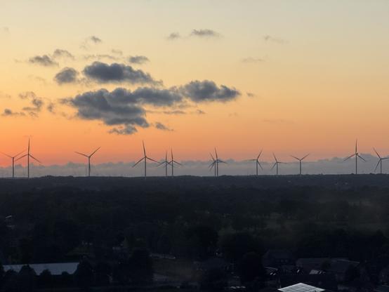 A sunset landscape showing windmills silhouetted on the horizon