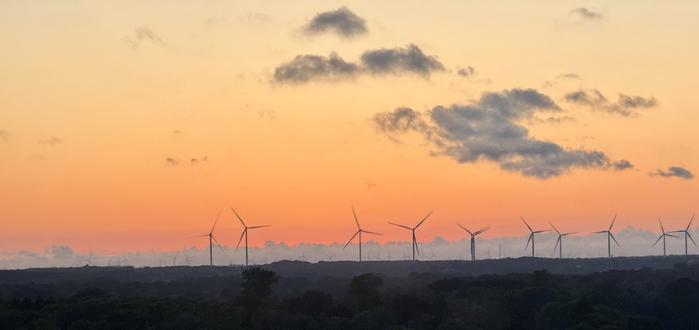 Sunset scene showing windmills silhouetted against the orange sky