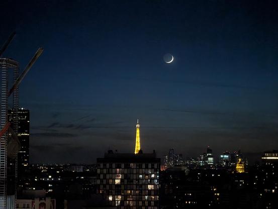 Lune très fine flottant au-dessus de la tour Eiffel et la Défense.
