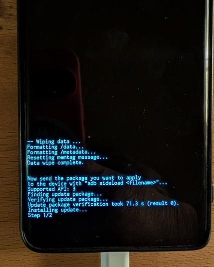 Photo of phone with black terminal screen loading a package