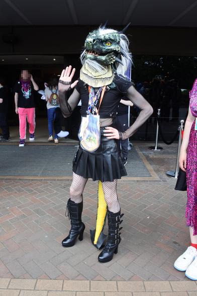 Fursuit photo - a dragon in a leather miniskirt and leather boots poses outside the hotel lobby at Confuzzled 2025