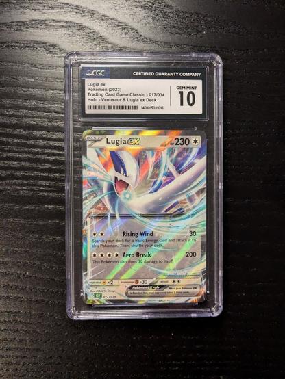 The image shows a graded Lugia V Pokémon card.

It is encased in a protective slab with a label at the top indicating a perfect grade of "10."

The card itself features Lugia, a legendary Pokémon, and has a holographic or foil effect. 

The slab is placed on a dark, textured surface.