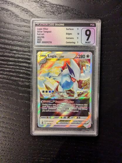 The picture shows a graded Lugia VSTAR Pokémon card encased in a slab. 

The card is graded as a 9, which is indicated on the label at the top of the holder.

The card itself has a colorful and dynamic design.