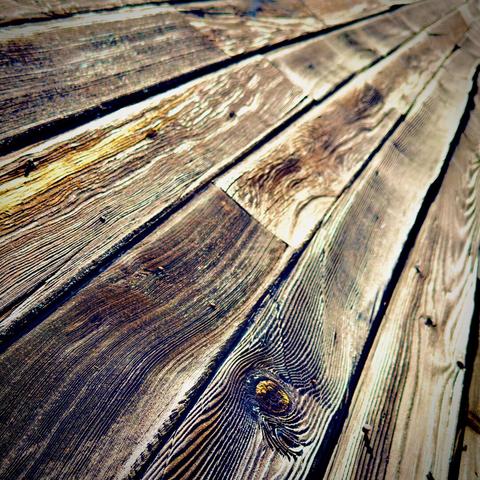 Long, slightly warped two-by-four planks of wood rest fastened, side by side in an upward, diagonal angle off into the blurry distance.