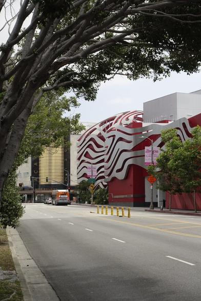 Gehry-designed Petersen Automotive Museum framed by arching branches of a tree.
