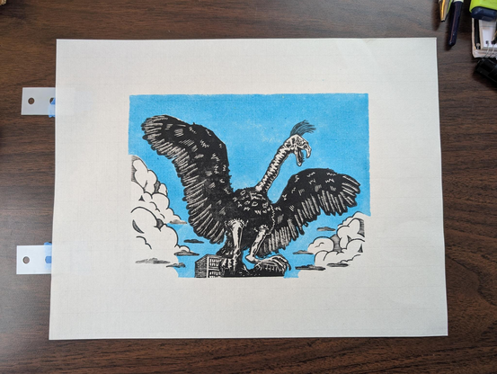 A color image of a linocut/woodcut print of the titular monster from the movie "The Giant Claw". The background of the print is a light sky blue, printed with carved linoleum. The main layer was printed in black with a wood block, which lends it much finer detail. It is an image of a large, lumpy, vulture-like bird. Its wings are spread wide, and it is perched (I use the term loosely, as its legs are very floppy) atop a partially crumbled building. It's neck is somehow lumpier than its body, and far too long, and its beak is crooked and lined with teeth, just for good measure. It is crowned with a tiny tuft of crazily forward-swept hair, as if a sudden gust just disturbed its combover. It looks very pleased with itself, as I suppose would befit a monster recently arrived from an antimatter galaxy. To complete the composition, it is flanked on the left and right by stylized cloud banks. The overall impression is that of an especially lumpy bird reveling in some recent mischief.