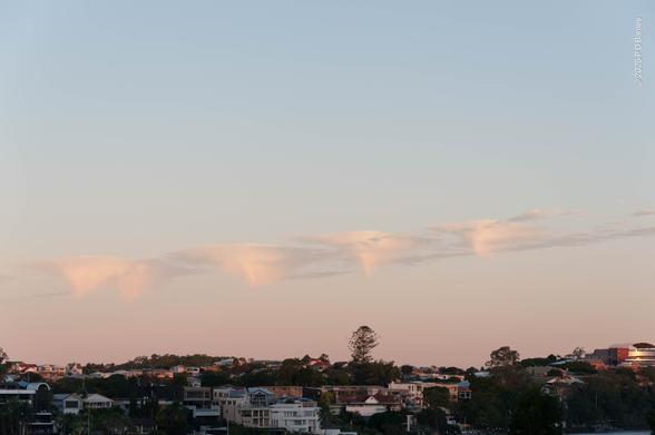 A series of almost identical, inverted-cone shaped clouds in a line, in an otherwise cloudless sky. Clearly the result of some quirk of wind and humidity.