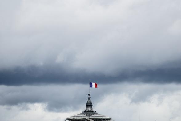 Top of the Grand Palais in Paris with a french flag and a cloud front in the background