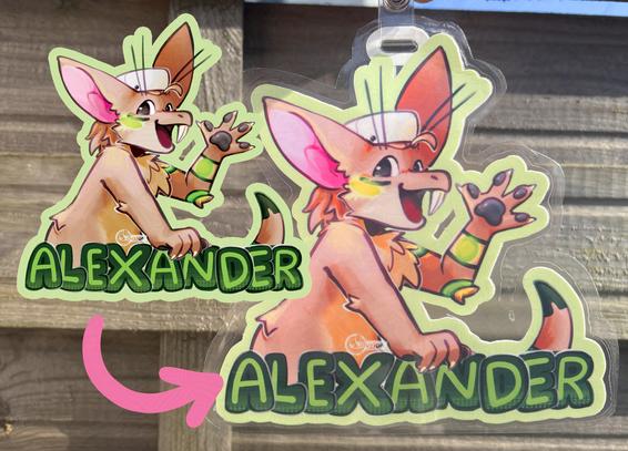 a printed and laminated convention badge featuring a tan-coloured yinglet with green accents and a chef hat, waving cheerfully