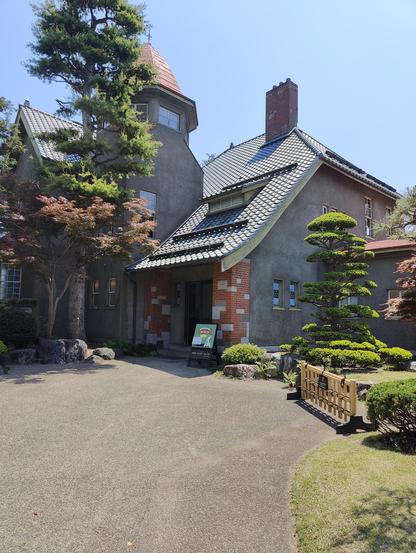 A photo of an antique house turned into a cafe. The architecture shows both Japanese and European influences. It is a beautiful day.