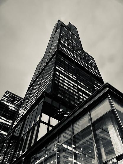 Black-and-white photo of the Sears Tower (it’s not called anything else. shut up) from a low angle.