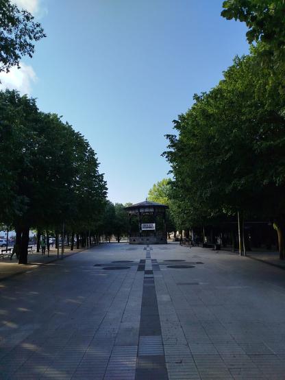 Plaza bat, musika kioskoa, zuhaitzez inguratuta eta zeru urdinarekin. Pankarta bat, zergatik egiten duzu espainolez?