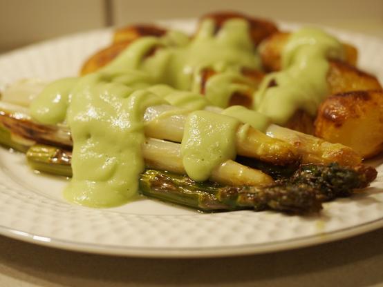 Gebackene Kartoffeln und grüner und weißer Spargel auf einem Teller. Über beidem wurde großzügig die Avocadosauce gegeben.