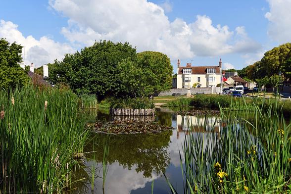 Photo of the village pond viewed from the south. The house reflecting in the water is The Elms, built by William Ridge in 1745, rented by Rudyard Kipling from 1897 until 1902. Rottingdean, City of Brighton & Hove, UK.