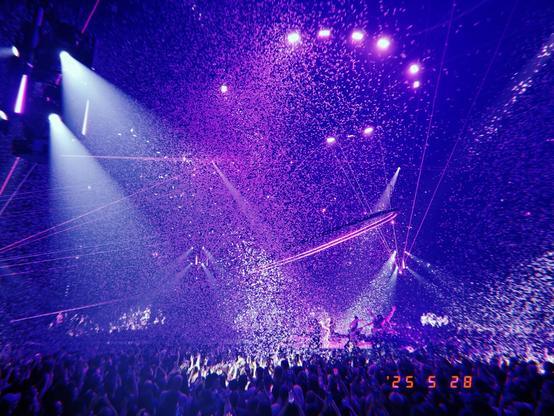 The stage centred while paper is raining from the ceiling. purple lights and a huge crowd in the background of thw O2 arena.