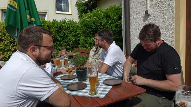 ein paar Männer sitzen beim Wirt am Tisch bei einem Bier