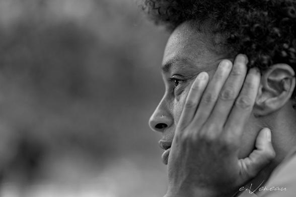 Portrait of a woman in profile holding her head in her hand.