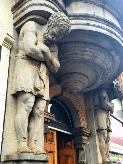 A pair of large atlantes figures surrounding the door of a Glasgow building.
