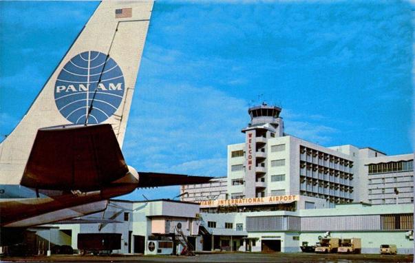 On the left and upfront is the tail of the Pan Am plane. Center right is the terminal. All under blue skies.