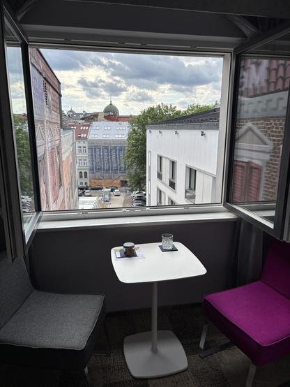 Large hotel window fully open, revealing the city beyond.