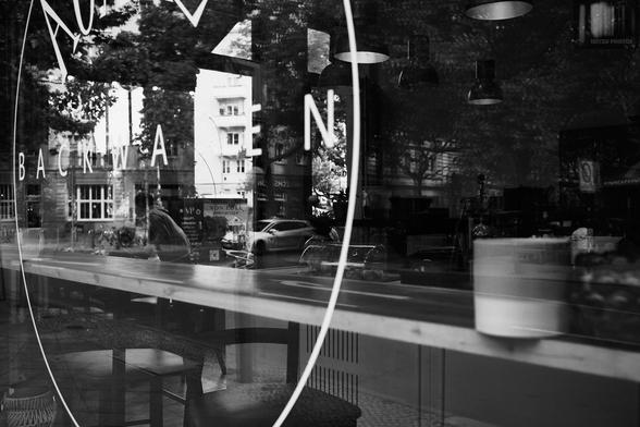 Monochrome street photography through the window of a café in Berlin, Germany.