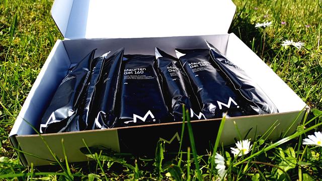 Eine offene Pappschachtel mit schwarzen Gels liegt im Gras.