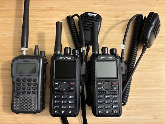 Desktop photo of two Anytone AT-D878UV radios and a Uniden BC246T scanner. Charging batteries and getting frequencies setup for weekend support event.