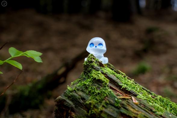 small sprite figure on mossy log in woodland
