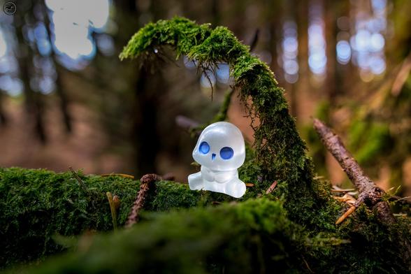 small sprite figure on mossy log in woodland