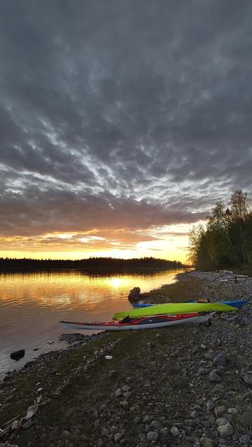 Three kayaks on a stony beach at sunset