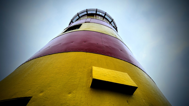 direkt am Turmfuß stehend blickt man aus der Froschperspektive den gelb-rot geringelten Leuchtturm von Pilsum hinauf.