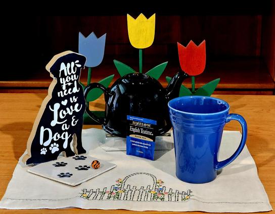 Tea tableau in black, white, and blue, with hints of bright colors, depicting a beloved dog, his ball, and his pawprints in a garden setting. The tea is English Teatime from Bigelow.