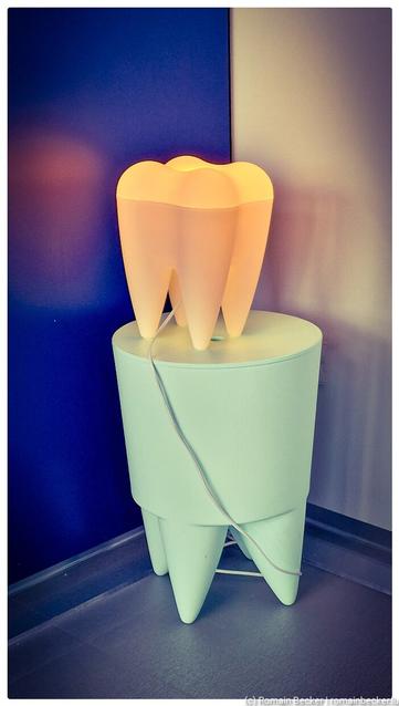 A toothshaped lamp on a small desk in a corner of a room.
