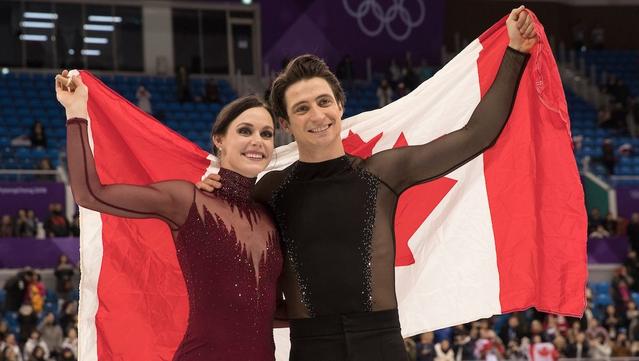Tessa Virtue et Scott Moir, figures emblématiques du patinage artistique canadien, photographiés tenant un drapeau canadien après une compétition.