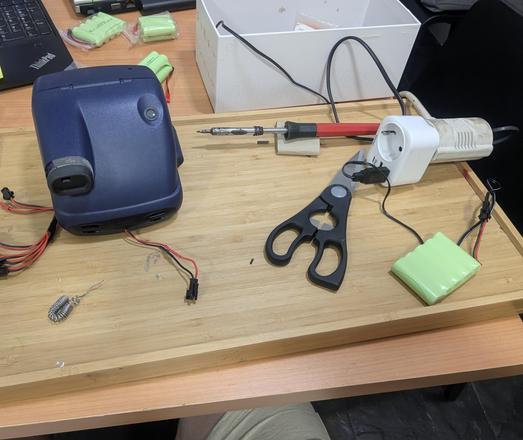 soldering setup. You can see wires coming out of a vintage Polaroid 600af camera with a small female connector on one side and a ni-mh battery charging from a usb cable on the right side