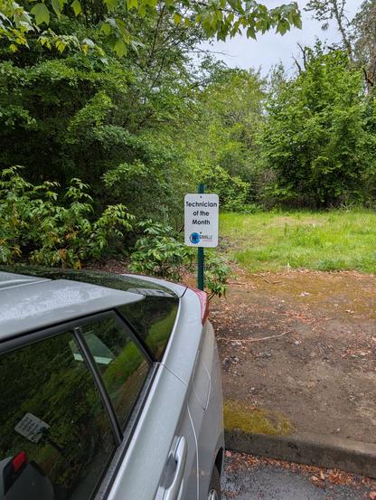 A car parked in a spot marked "technician of the month".