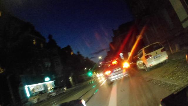 POV Radfahrer: Ein BMW steht rechts blinkend auf dem Radfahrstreifen, schräg hinter dem Fahrzeug ist eine freie Parklücke.