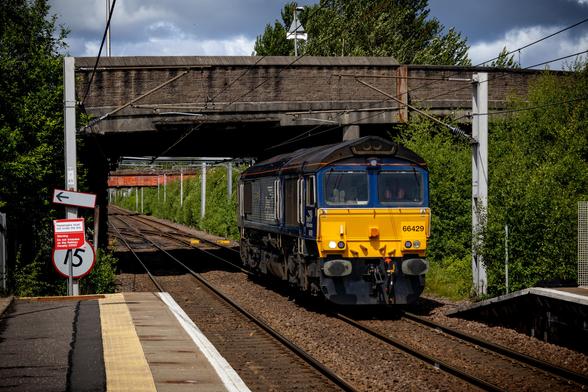 DRS-owned locomotive, 66429, light-loco moving through Whifflet station. In the left window you can clearly see the secondman's shoe soles, showing that they have their feet up.