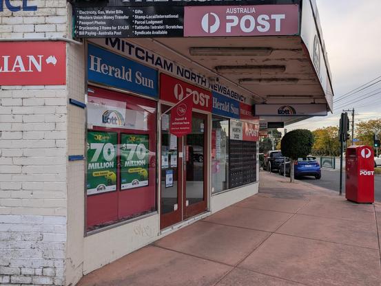 Photo of the front of the Mitcham North Newsagency with Herald Sun, Australia Post and Tattslotto signs and posters covering the frontage