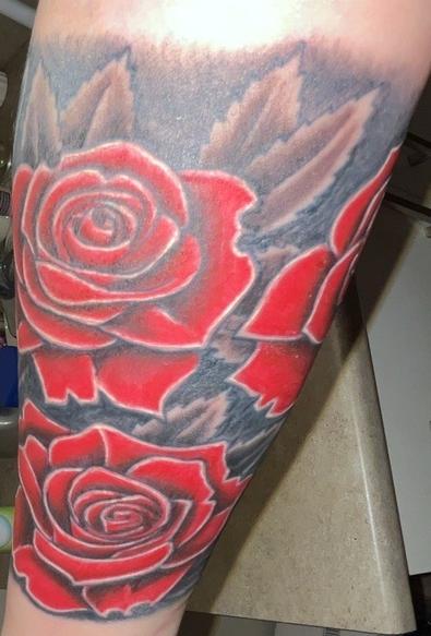 The inside of my forearm, where the wild roses grow
PD: Tattoo of three large red roses with bold, vivid coloring. The petals are filled with a rich, vibrant red that is mostly uniform but includes subtle variations—some areas are a deeper, darker red, especially near the base of the petals or where they overlap, while the outer edges are brighter. This shading creates a sense of layering and depth, giving the petals a slightly three-dimensional look. Each petal is sharply defined with a thin white outline, creating a glowing effect and making each petal stand out distinctly from the others and from the background. The roses are not hyper-realistic but have a stylized, illustrative quality, with clear, graphic lines and strong contrast. The background and spaces between the roses are shaded in black and gray, with a smoky, cloud-like effect. This dark shading enhances the intensity of the red roses and adds to the dramatic appearance of the tattoo. The overall coloring style is bold and graphic, emphasizing the shape and structure of the roses rather than aiming for a soft, naturalistic look.