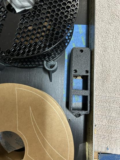 The inside wall of the FilaBilly Humidor has the power outlet housing installed and two empty filament reels in the places where filament reels will go.  Instead of standing up, it is lying on a towel.